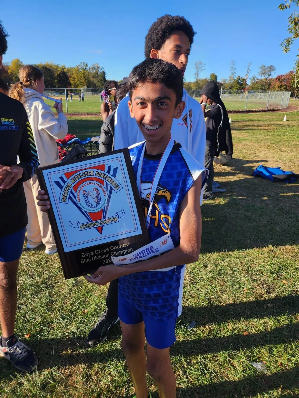 Anish smiling and holding a Greater Middlesex Conference Blue Division Champion plaque