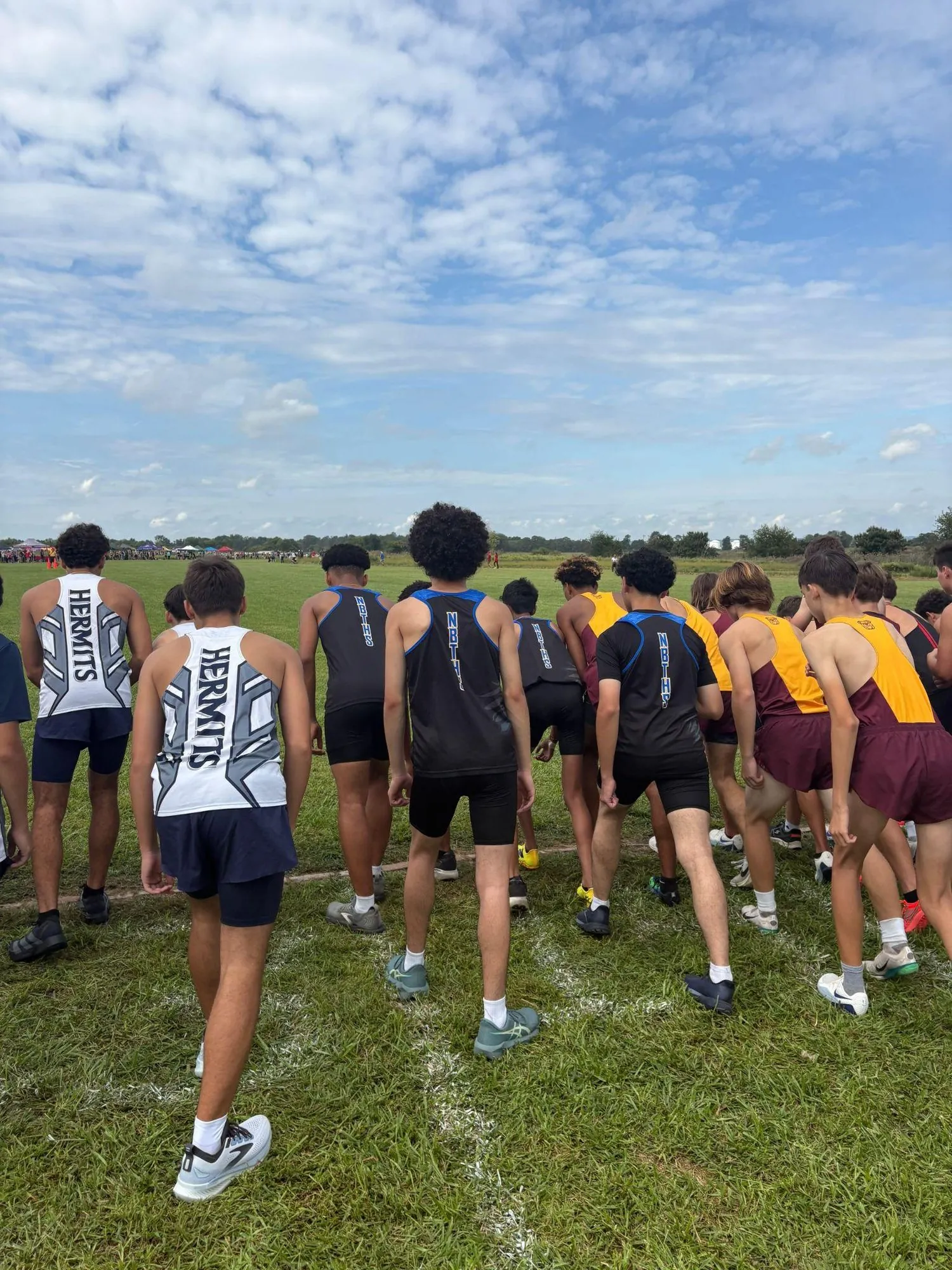Runners from several schools crouched at a start line under a cloudy sky