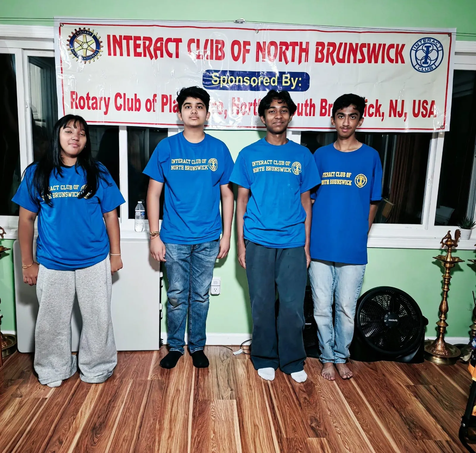 Four club members standing beneath the Interact Club of North Brunswick banner