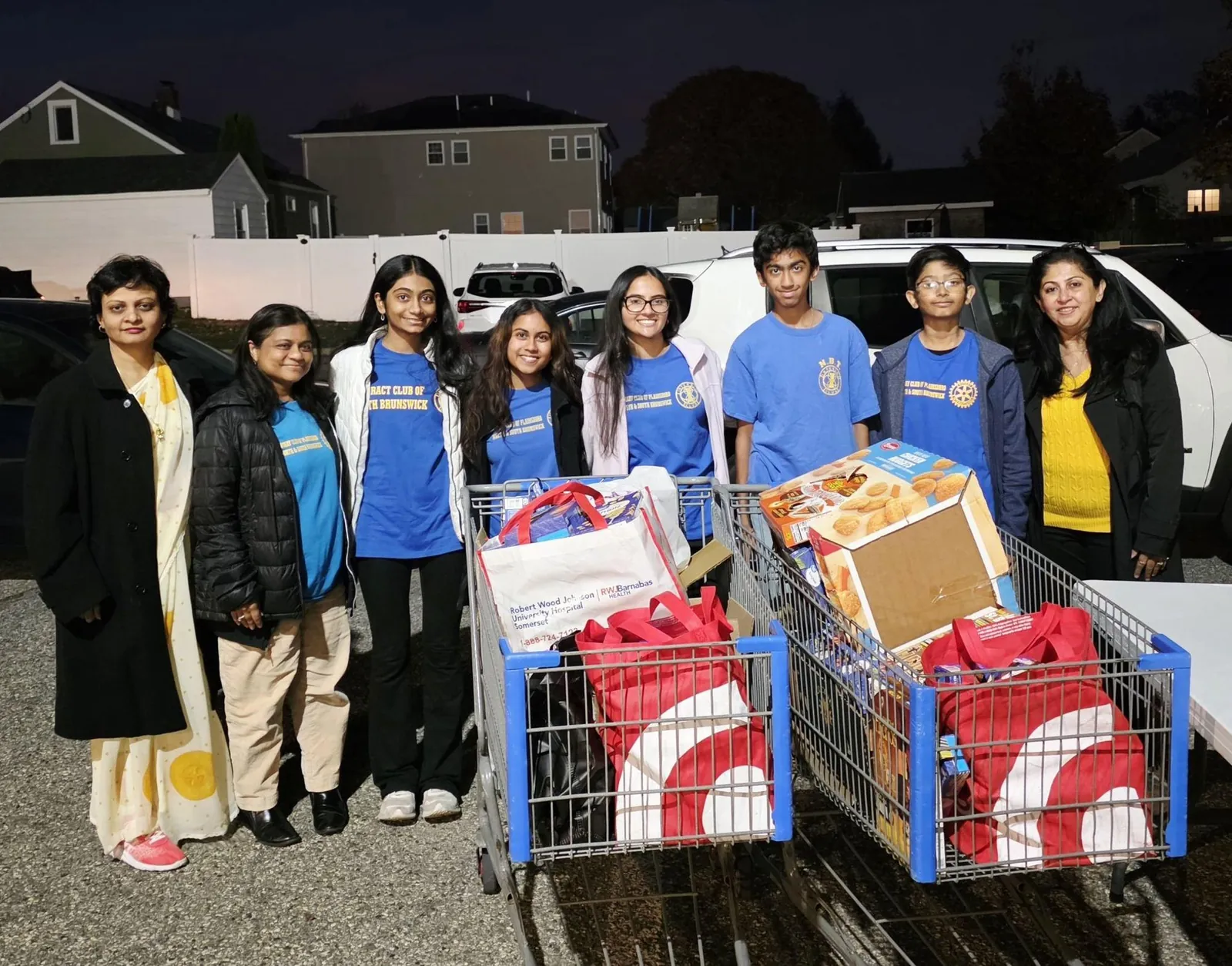 Club members and adults standing behind two shopping carts full of donated food