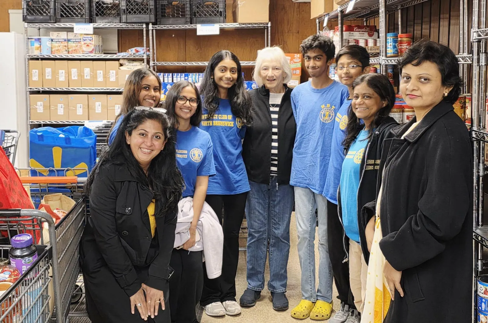 Club members inside a food pantry with stocked shelves