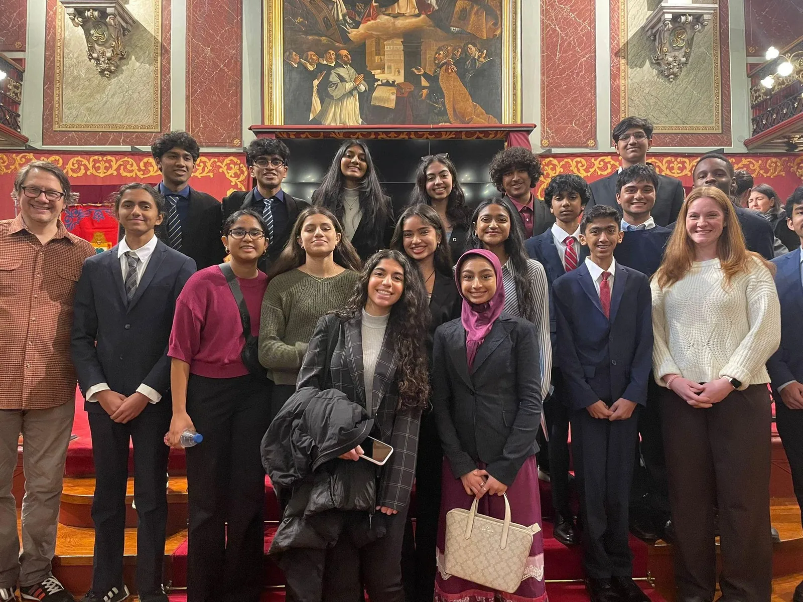 Large delegation group photo in an ornate hall with red and gold walls